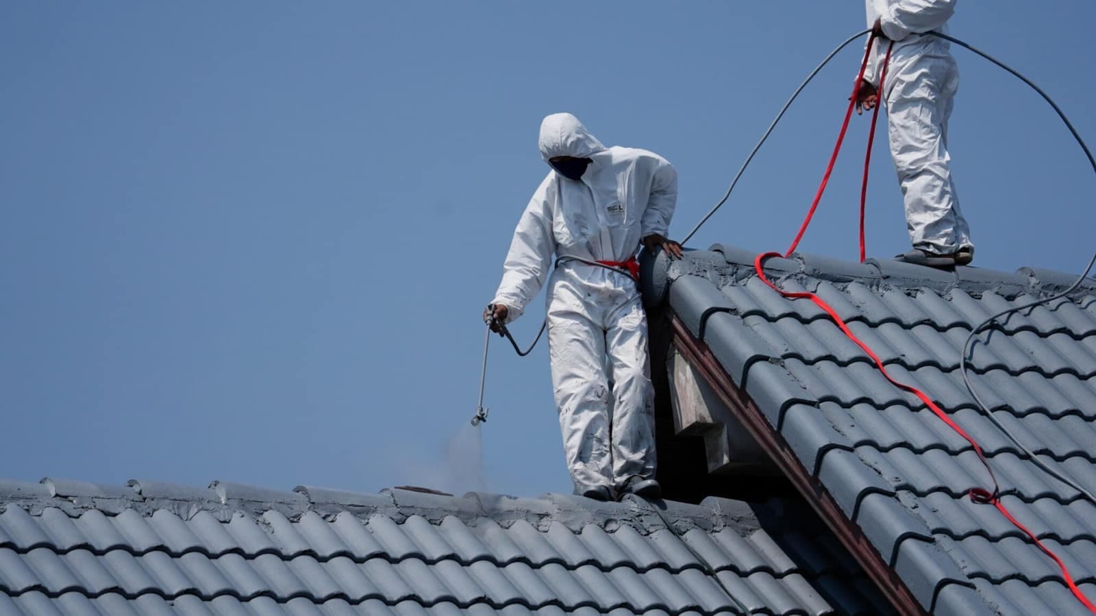 Roofer standing on roof spray painting